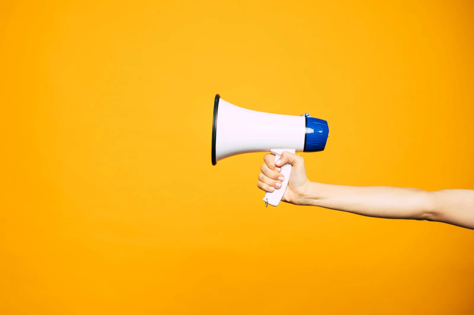 On a bold, dark yellow background a white, blue and black megaphone demonstrates the concept of marketing a video via b00st.com for YouTube Trueview ads, Meta ad brands Facebook and Instagram, TikTok, Google Ads and other platforms.