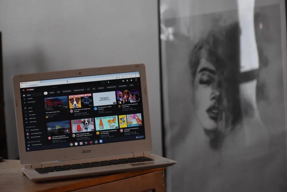A laptop screen displaying YouTube next to an piece of artwork on the wall to demonstrate how b00st.com advertising clients grow their brands online.