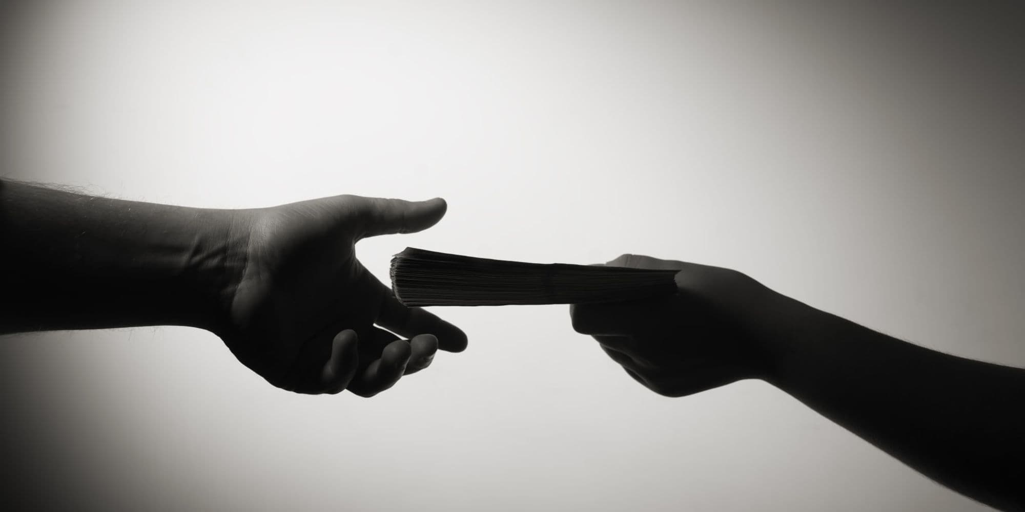 Money exchanging hands with a dark background contrast. Looks and feels of evil, shady business dealings, a reference to questionable influencer marketing tacticts online.